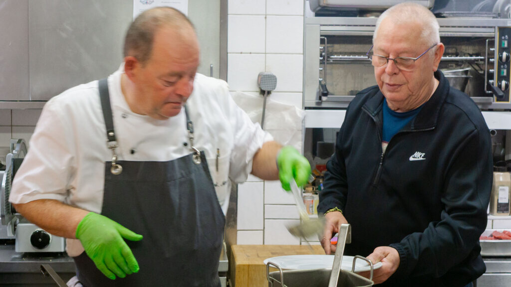 Der Chef Andreas Männle legt einem Gast während der Küchenparty Essen auf den Teller